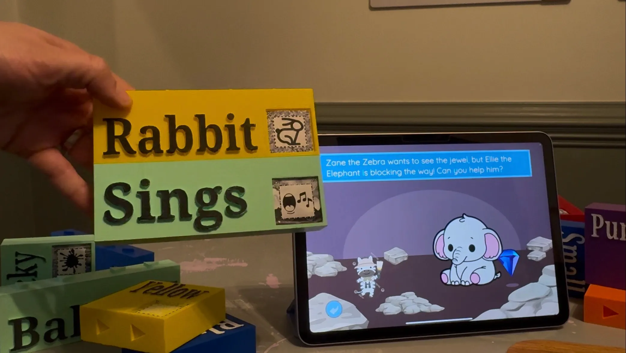 The UI of the StoryBlocks application running on an iPad, next to two of the StoryBlocks interlocking building blocks.